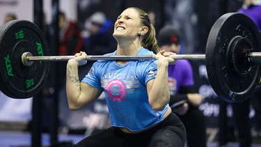 Eine Sportlerin trainiert mit schweren Gewichten. Wer exzessiv trainiert, kann extreme Muskelschmerzen und Rhabdomyolyse bekommen.  | Bild: picture-alliance/dpa